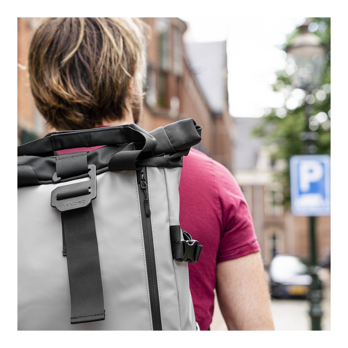 WANDRD PRVKE 31-Liter DisNet Grey Photo Bundle - Anwendungsbeispiel: Rückenansicht des grauen Roll-Top-Rucksacks mit Detailansicht des Verschlusses und seitlichen Reißverschlusses