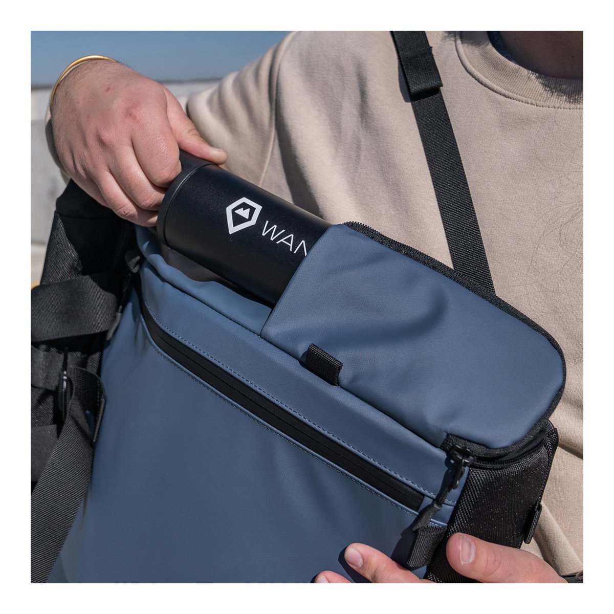 WANDRD PRVKE Lite 11-Liter Blue - Anwendungsbeispiel: Hand steckt schwarze Trinkflasche in die Seitentasche eines grauen Rucksacks. WANDRD PRVKE Lite 11-Liter Blue - Anwendungsbeispiel: Hand steckt schwarze Trinkflasche in die Seitentasche eines grauen Rucksacks.