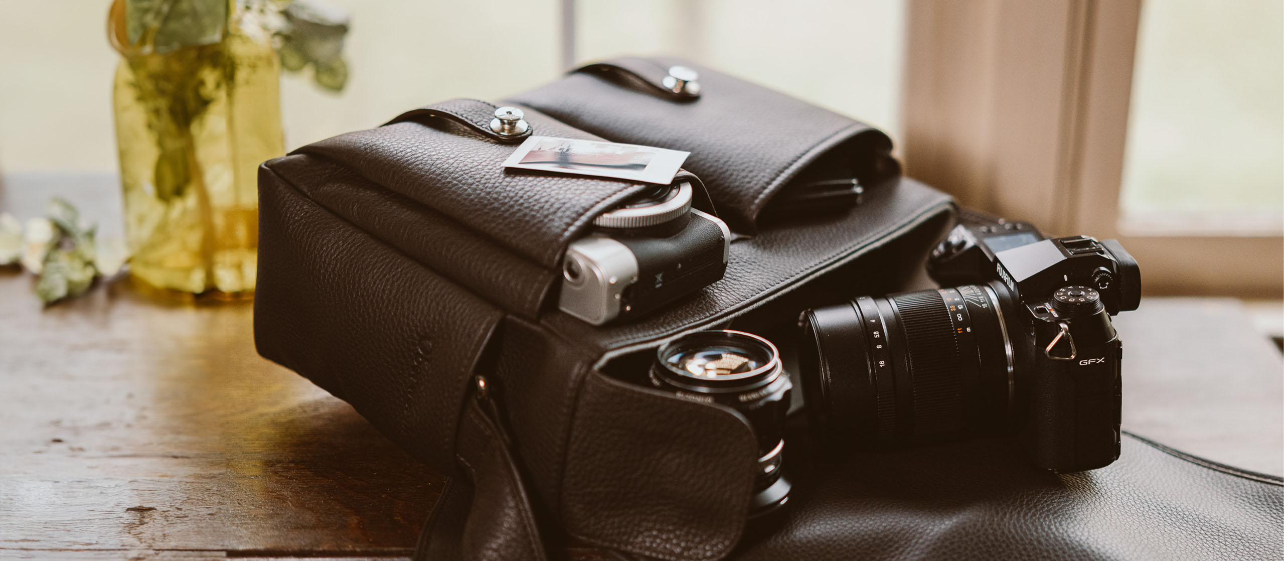 Kameratasche aus Leder von Oberwerth in einem dunklen braun  mit einer DSLR-Kamera und Objektiven steht offen und vollgepackt auf einem Tisch