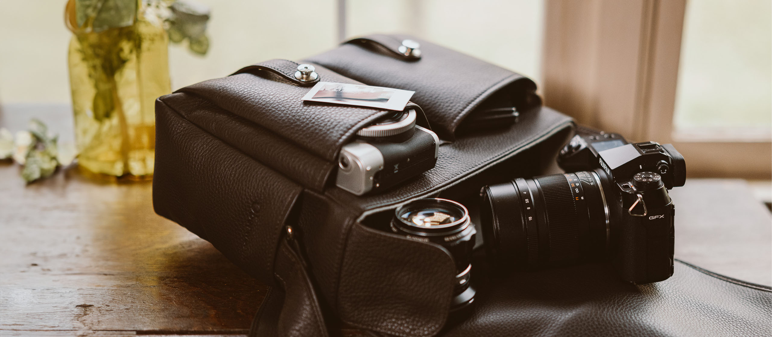 Oberwerth Ledertaschen für Fotografen Kameratasche aus Leder von Oberwerth in einem dunklen braun mit einer DSLR-Kamera und Objektiven steht offen und vollgepackt auf einem Tisch