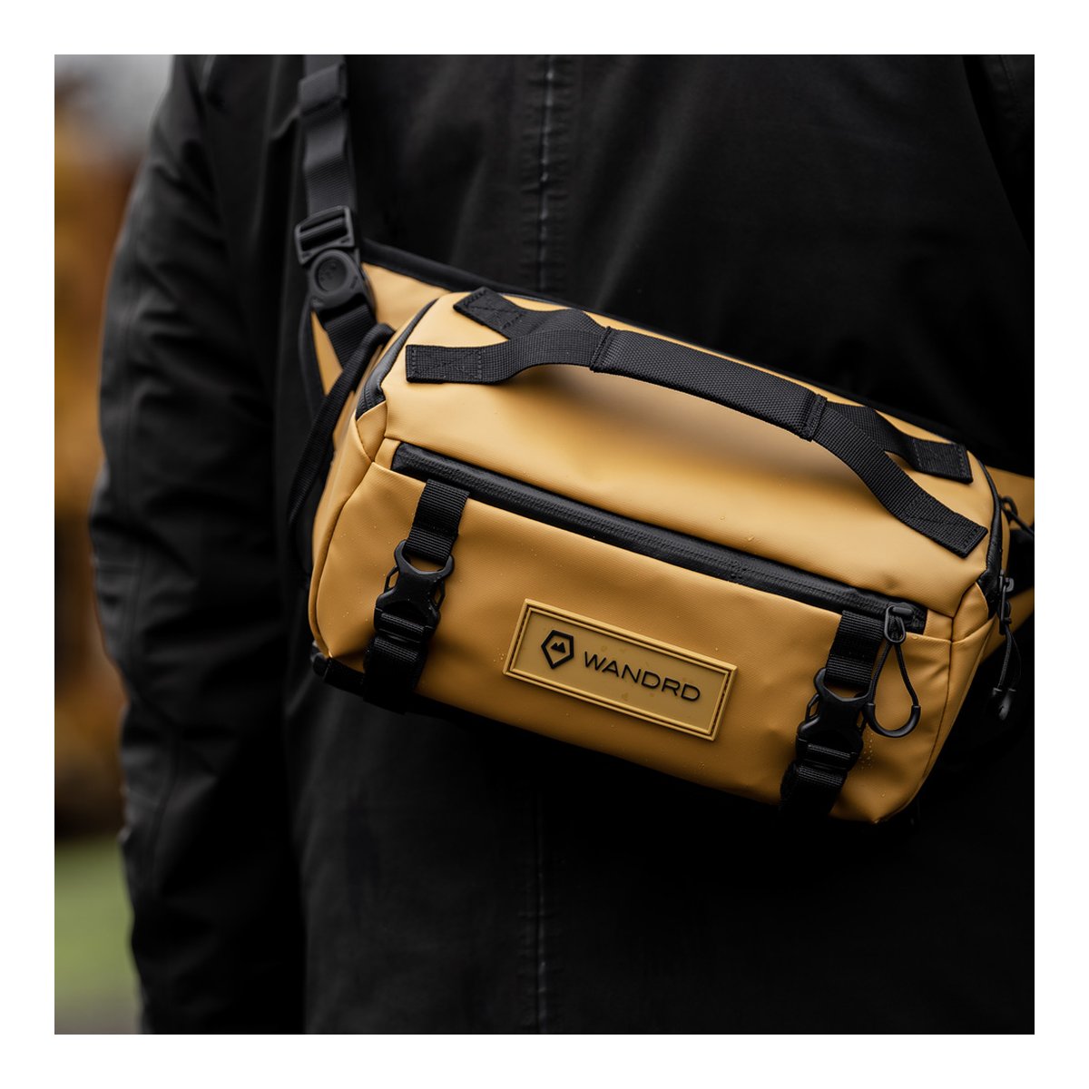 WANDRD ROGUE Sling 6L Dallol Yellow - Anwendungsbeispiel: Senfgelbe Sling Bag von vorne an einer Person getragen.