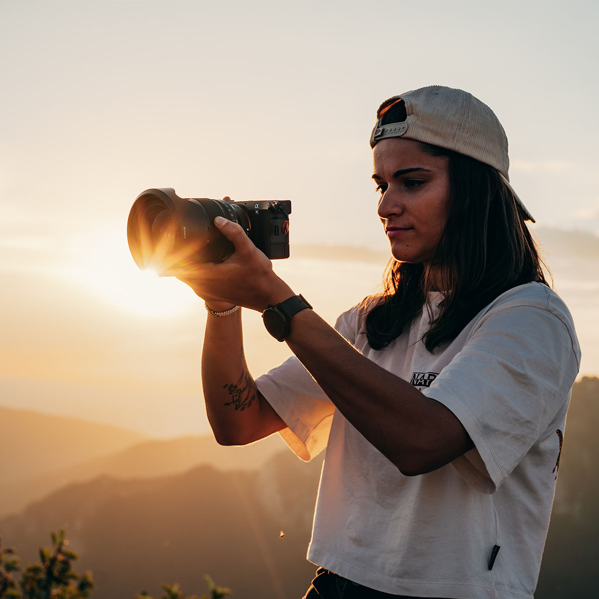 Sony Alpha 7C II Silber Gehäuse  33 MP Junge Frau mit weißer Cap und weißem T-Shit mit der Sony Alpha 7C II vor einem Sonnenuntergang fotografiert