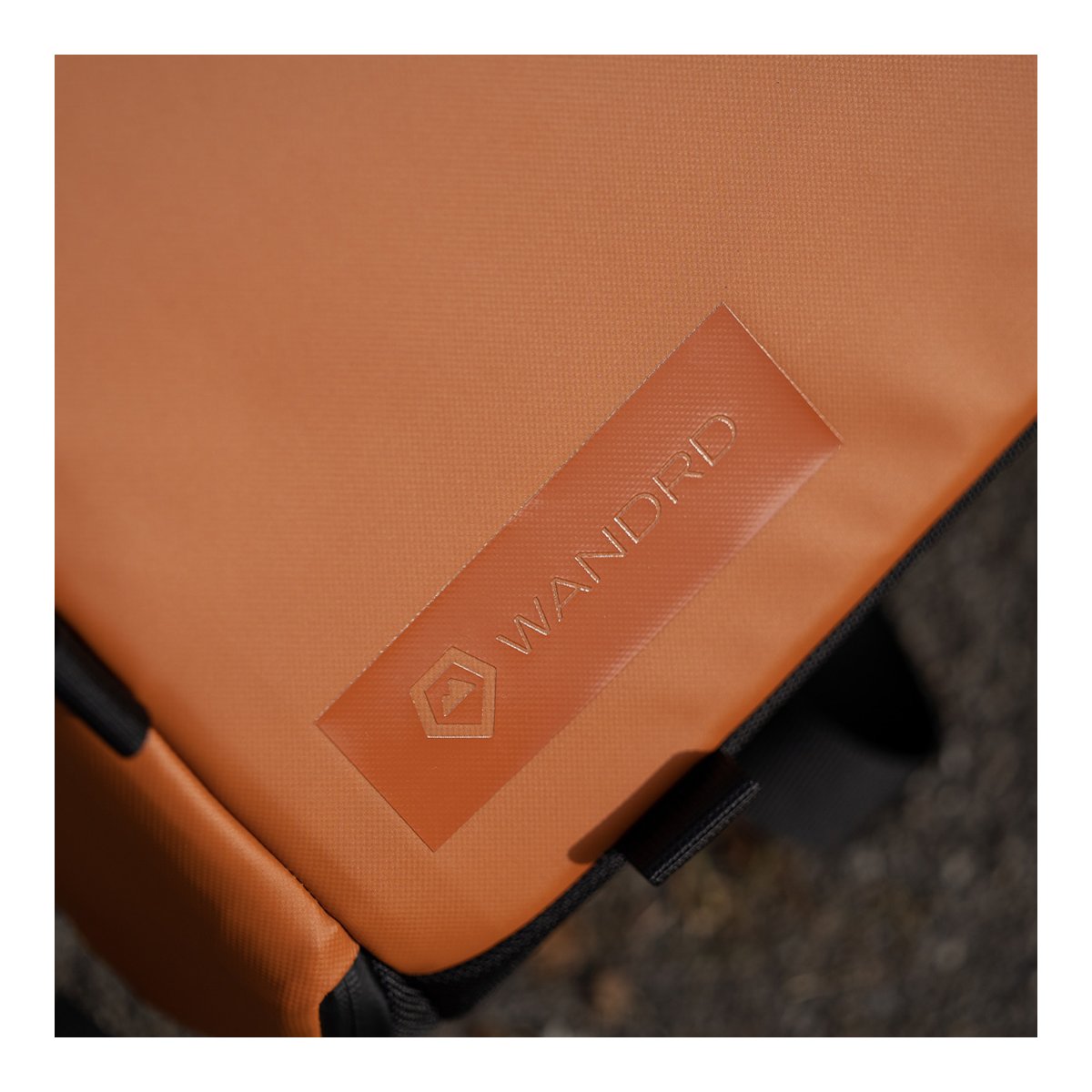 WANDRD PRVKE Lite 11-Liter Sedona Orange - Detailansicht des WANDRD Logos auf der orangefarbenen Produktoberfläche