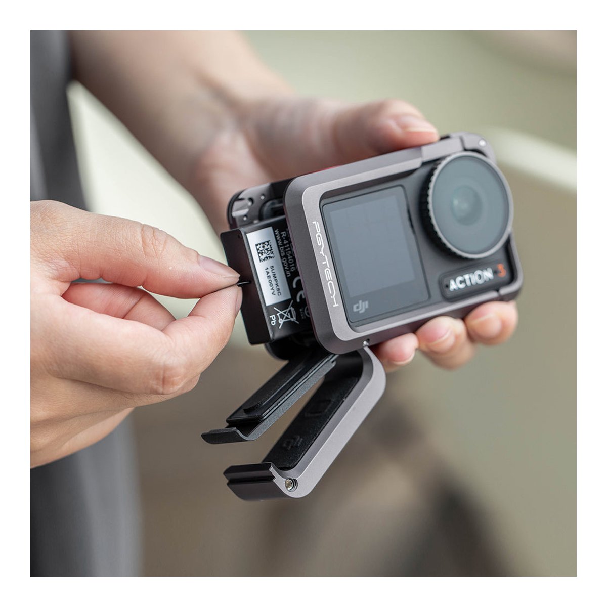 PGYTECH OSMO Action 3 Camera Cage - Anwendungsbeispiel: Hände entnehmen Akku aus DJI Action 3 Kamera mit PGYTECH-Rahmen.