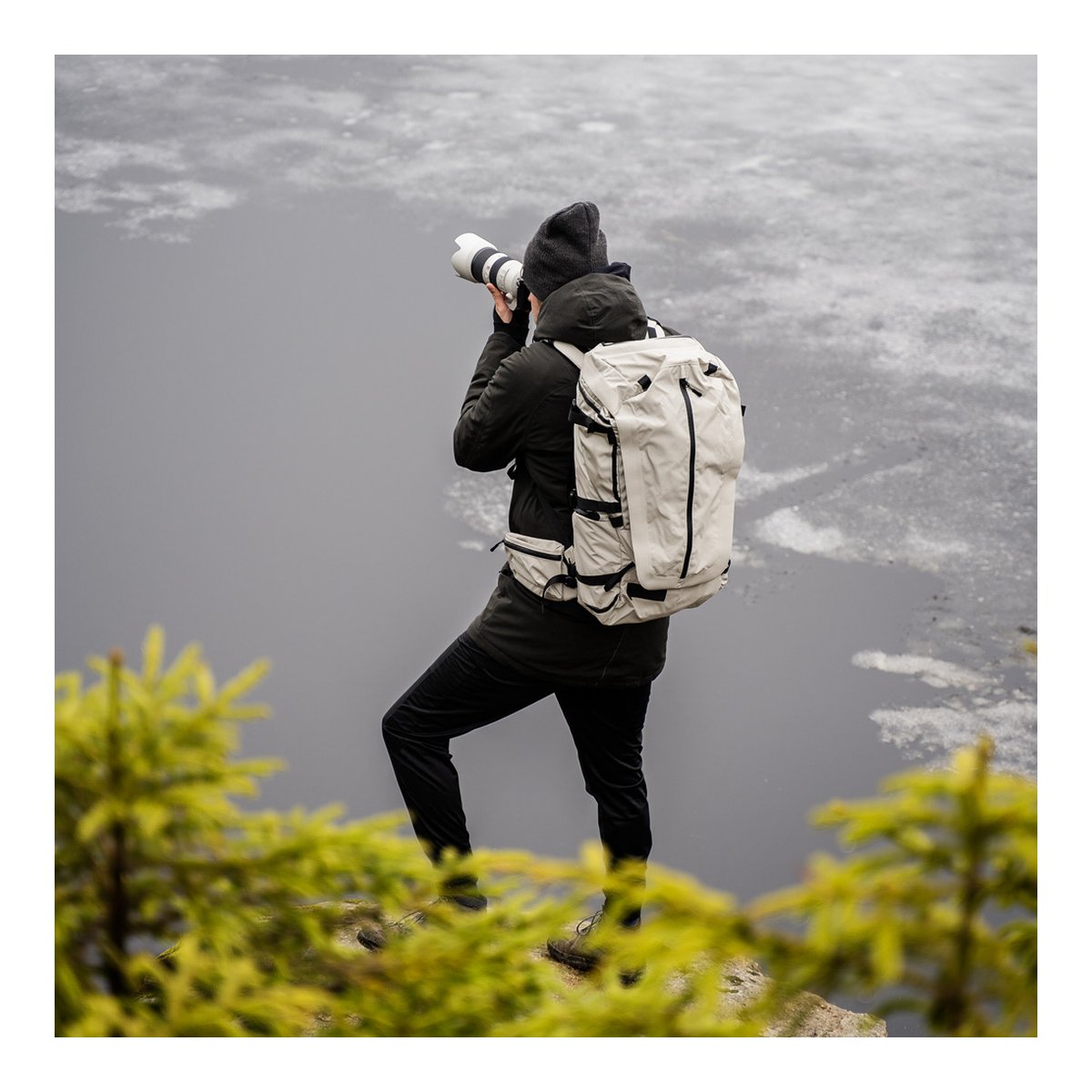 Wandrd Fernweh M/L Tan Photo Bundle - Anwendungsbeispiel: Rückansicht des Rucksacks an einer Person beim Fotografieren in der Natur.