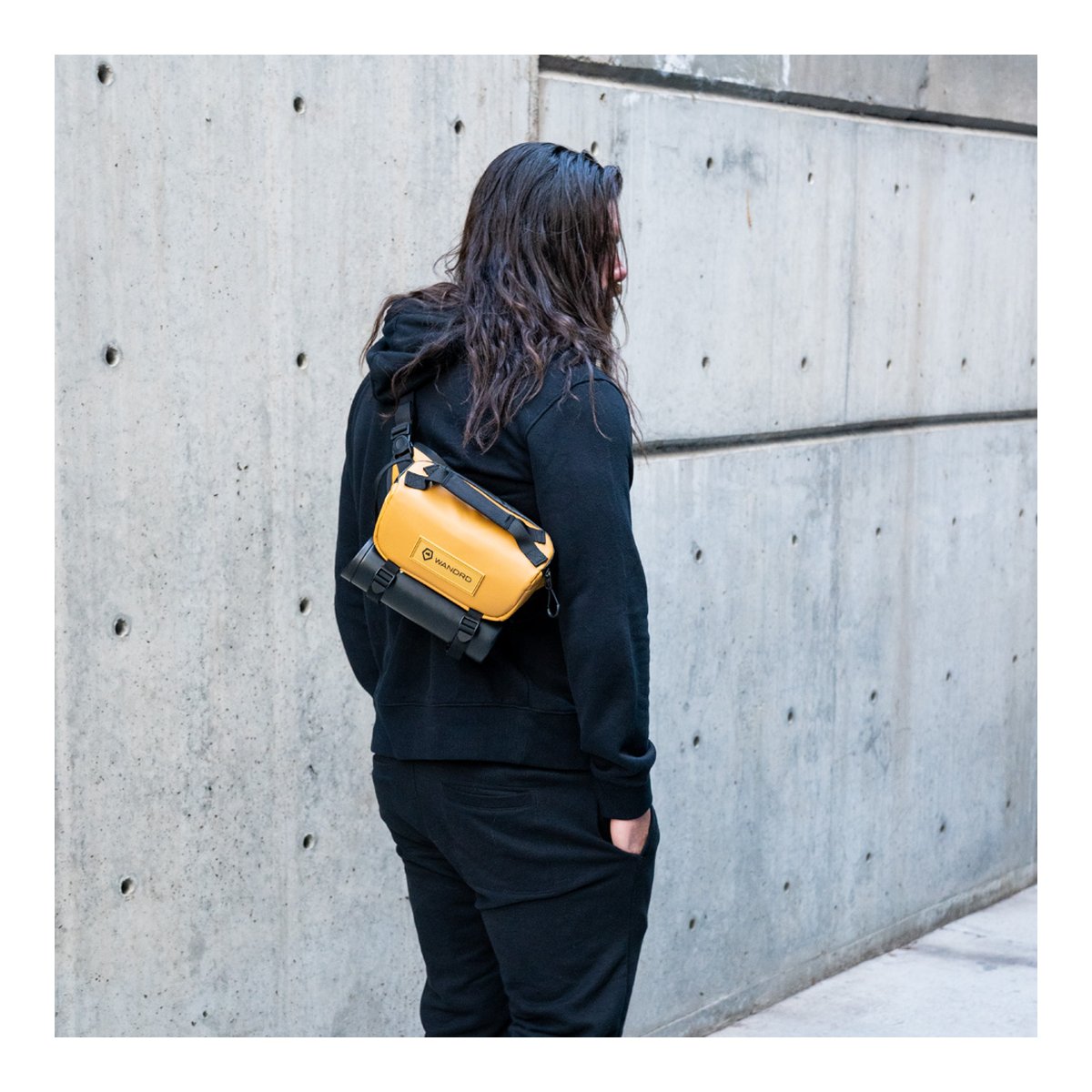 WANDRD ROGUE Sling 3L Dallol Yellow - Anwendungsbeispiel: Gelb-schwarze Sling Bag auf dem Rücken getragen.