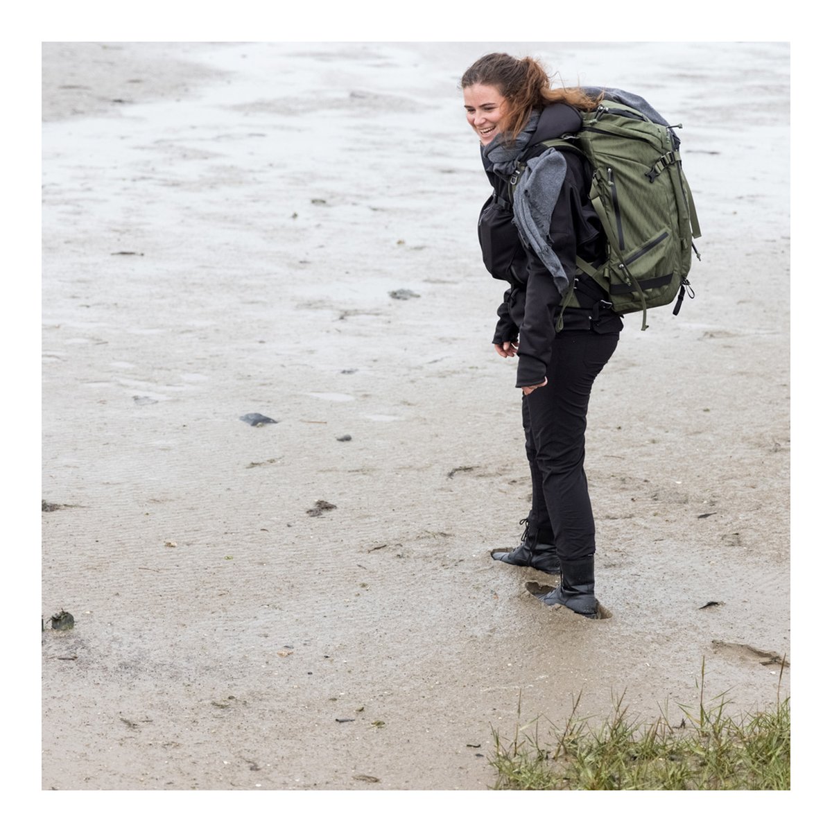 F-Stop DuraDiamond Tilopa - Zypresse - Anwendungsbeispiel: Frau trägt olivgrünen Rucksack in Wattlandschaft. F-Stop DuraDiamond Tilopa - Zypresse - Anwendungsbeispiel: Frau trägt olivgrünen Rucksack in Wattlandschaft.