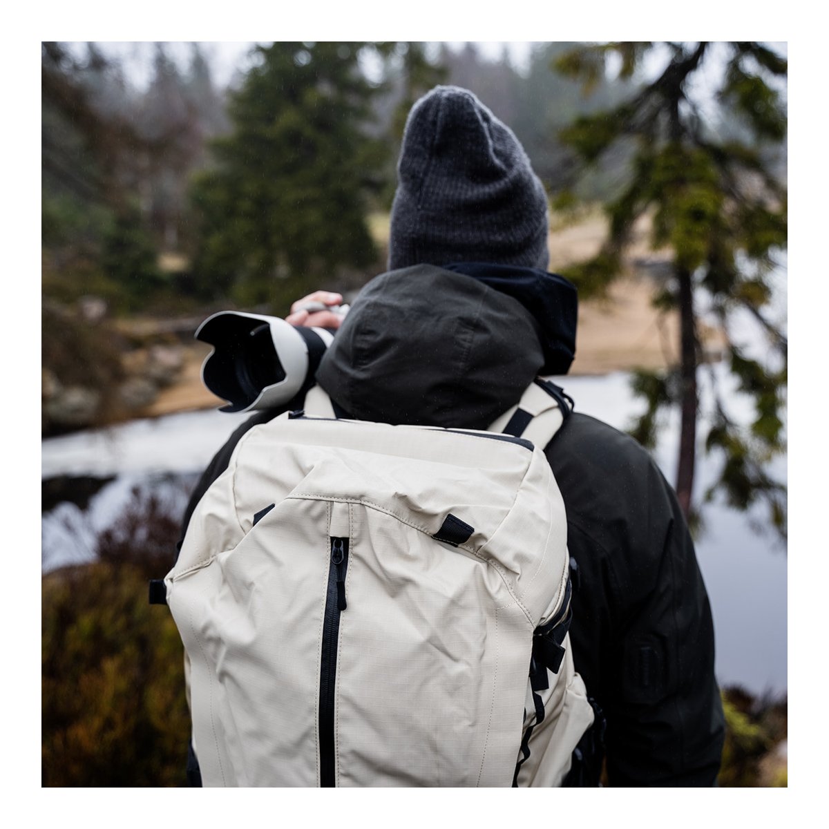 Wandrd Fernweh M/L Tan Photo Bundle - Anwendungsbeispiel: Rückansicht eines Fotografen mit beigem Rucksack in Natur