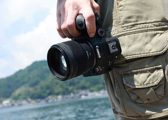 Canon EOS R Kamera mit RF 45mm 1.2 STM Objektiv wird outdoor am Wasser gehalten.