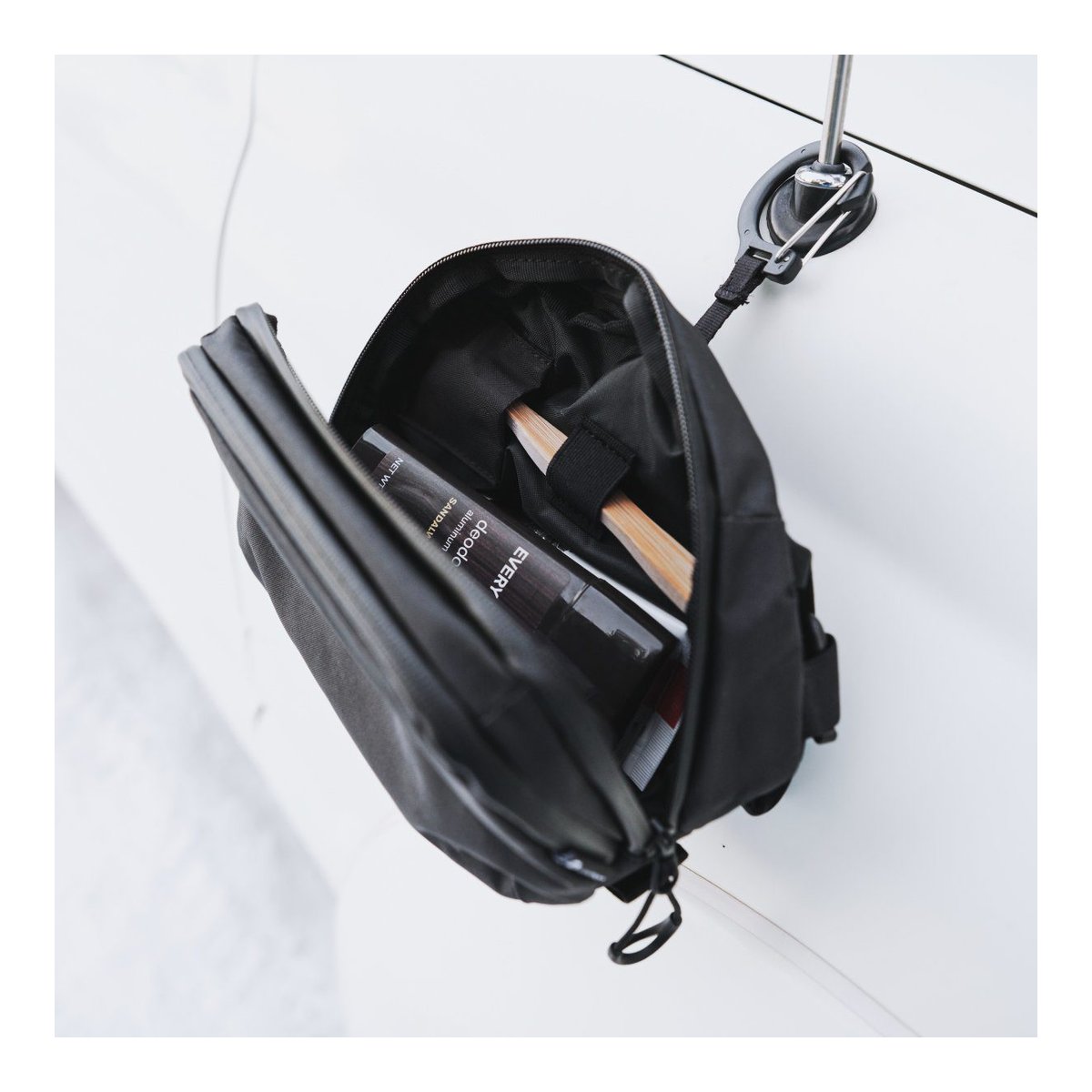 WANDRD Toiletry Bag Medium - Anwendungsbeispiel: Geöffnete Tasche mit Deodorant und Zahnbürsten hängend.