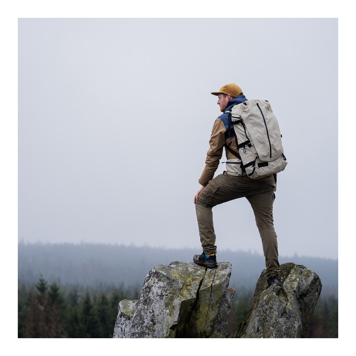 Wandrd Fernweh M/L Tan Photo Bundle - Anwendungsbeispiel: Rückansicht eines Wanderers mit Rucksack auf Felsen, {image_position}. Bild.