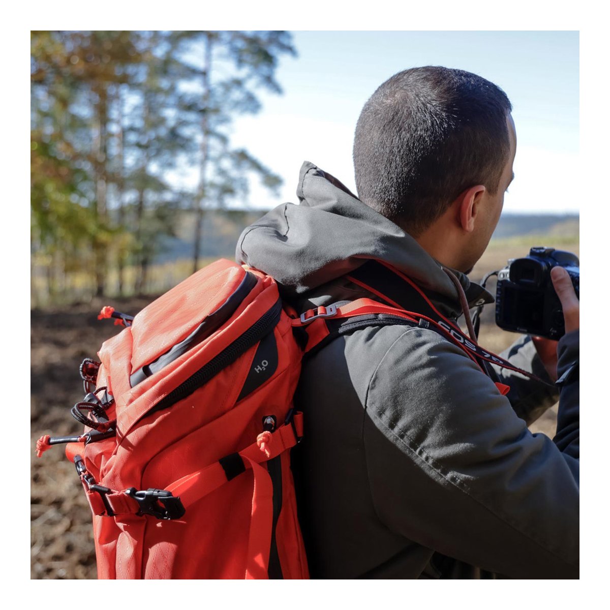 F-Stop DuraDiamond Ajna - Magma - Anwendungsbeispiel: Roter Rucksack von der Seite auf dem Rücken einer Person mit Kamera.