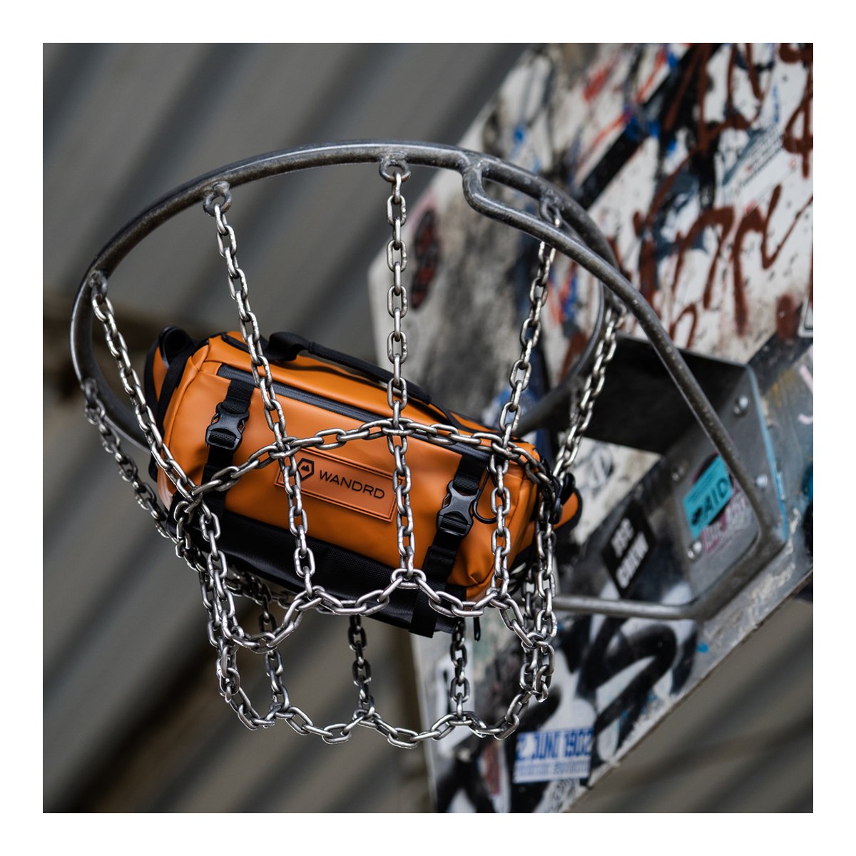 WANDRD ROGUE Sling 6L Sedona Orange - Anwendungsbeispiel: Orange WANDRD Tasche in einem Basketballkorb mit Kettennetz.