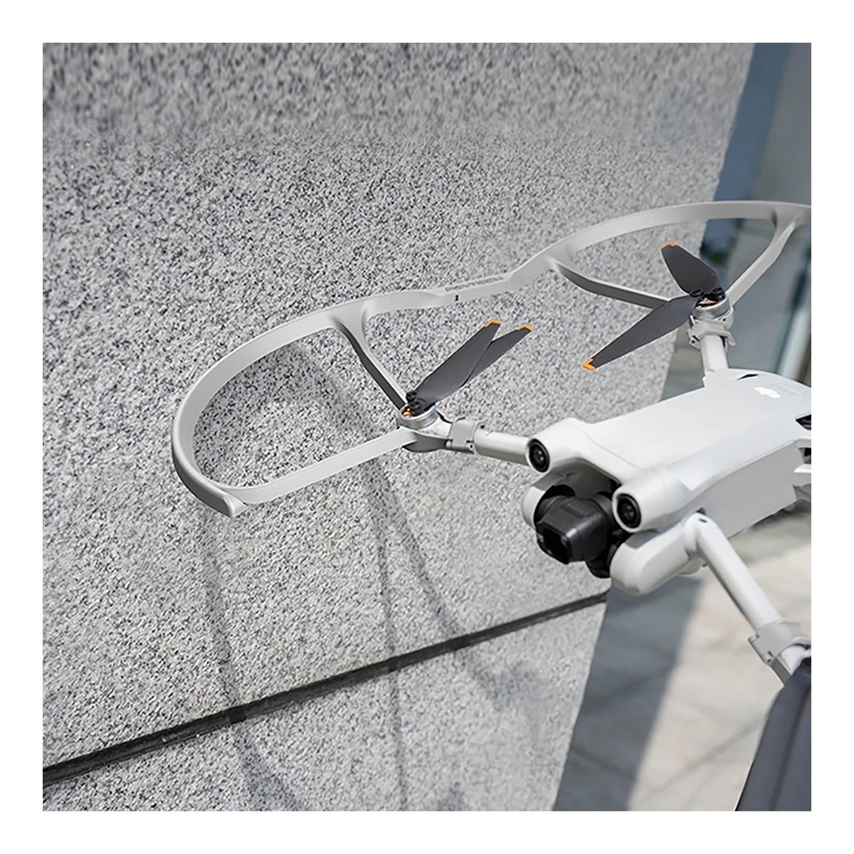 PGYTECH DJI Mini 3 Pro Propeller Guard - Detailansicht: Grauer Propellerschutz an weißer Drohne, nah an einer grauen Wand.