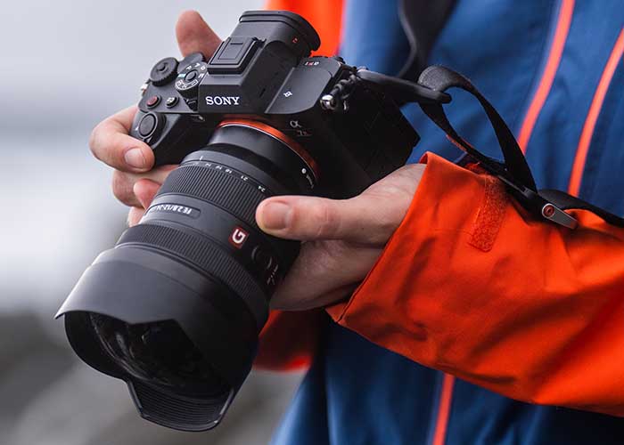 Person hält eine Sony Alpha 7R V mit Objektiv in der Hand bei einem Outdoor-Shooting.
