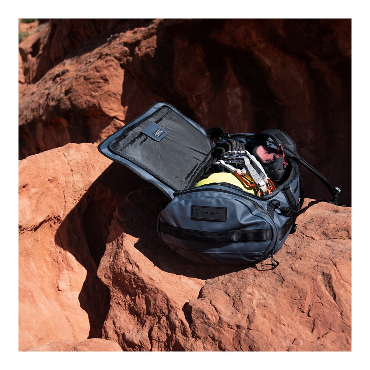 WANDRD HEXAD CARRYALL DUFFEL 40-Liter Aegean Blue - Anwendungsbeispiel: Geöffnete Tasche gefüllt mit Kletterausrüstung auf Felsen. WANDRD HEXAD CARRYALL DUFFEL 40-Liter Aegean Blue - Anwendungsbeispiel: Geöffnete Tasche gefüllt mit Kletterausrüstung auf Felsen.