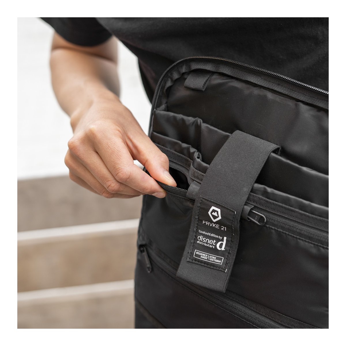 WANDRD PRVKE 21-Liter DisNet Grey Photo Bundel V3 - Detailansicht: Hand öffnet Reißverschluss einer schwarzen Tasche, Innenfächer sichtbar WANDRD PRVKE 21-Liter DisNet Grey Photo Bundel V3 - Detailansicht: Hand öffnet Reißverschluss einer schwarzen Tasche, Innenfächer sichtbar