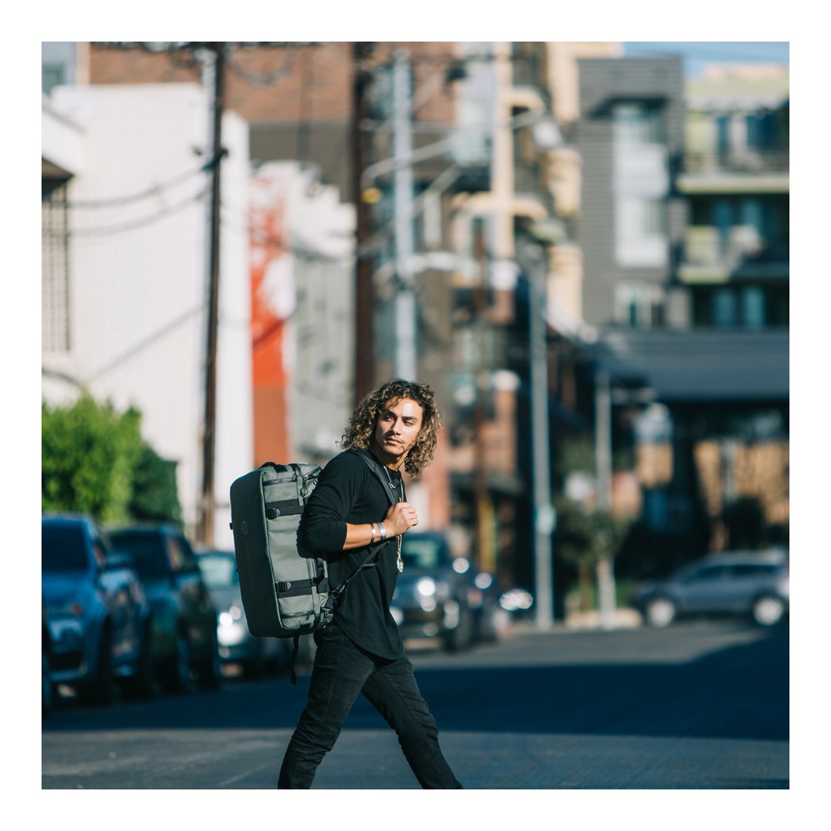 WANDRD HEXAD ACCESS DUFFEL Wasatch Green - Anwendungsbeispiel: Mann trägt graue Reisetasche diagonal auf urbaner Straße. WANDRD HEXAD ACCESS DUFFEL Wasatch Green - Anwendungsbeispiel: Mann trägt graue Reisetasche diagonal auf urbaner Straße.