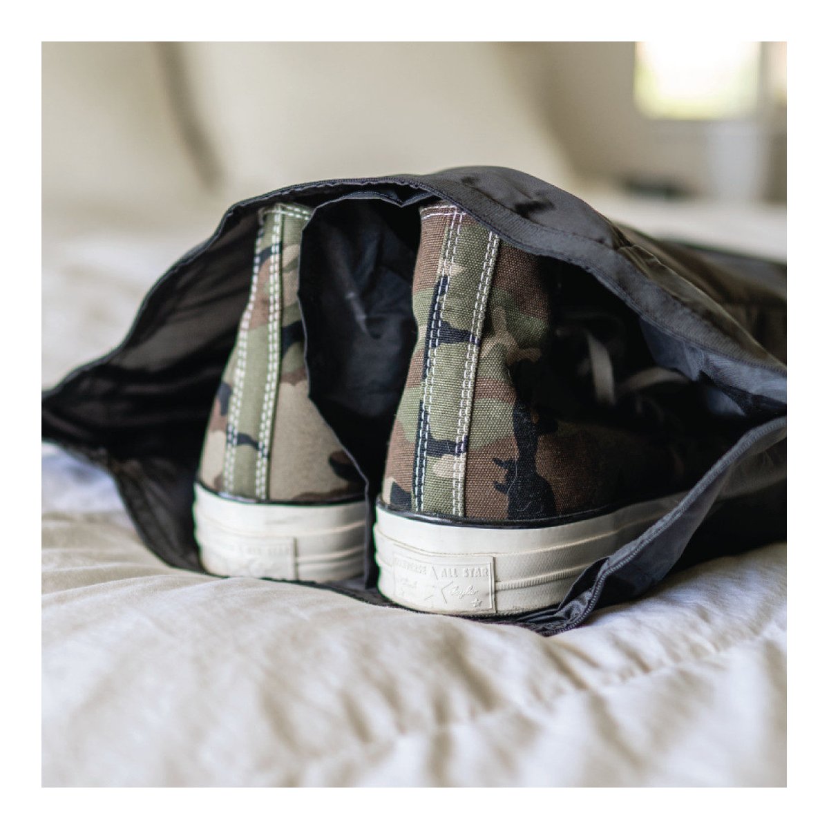 WANDRD Shoe Pouch - Anwendungsbeispiel: Rückansicht von zwei Camouflage-Sneakers in einem Schuhbeutel.
