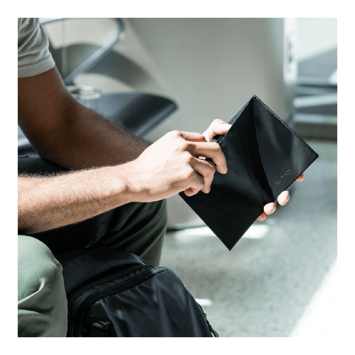 WANDRD Travel Wallet - Anwendungsbeispiel: Hände halten offenes schwarzes Kartenetui.
