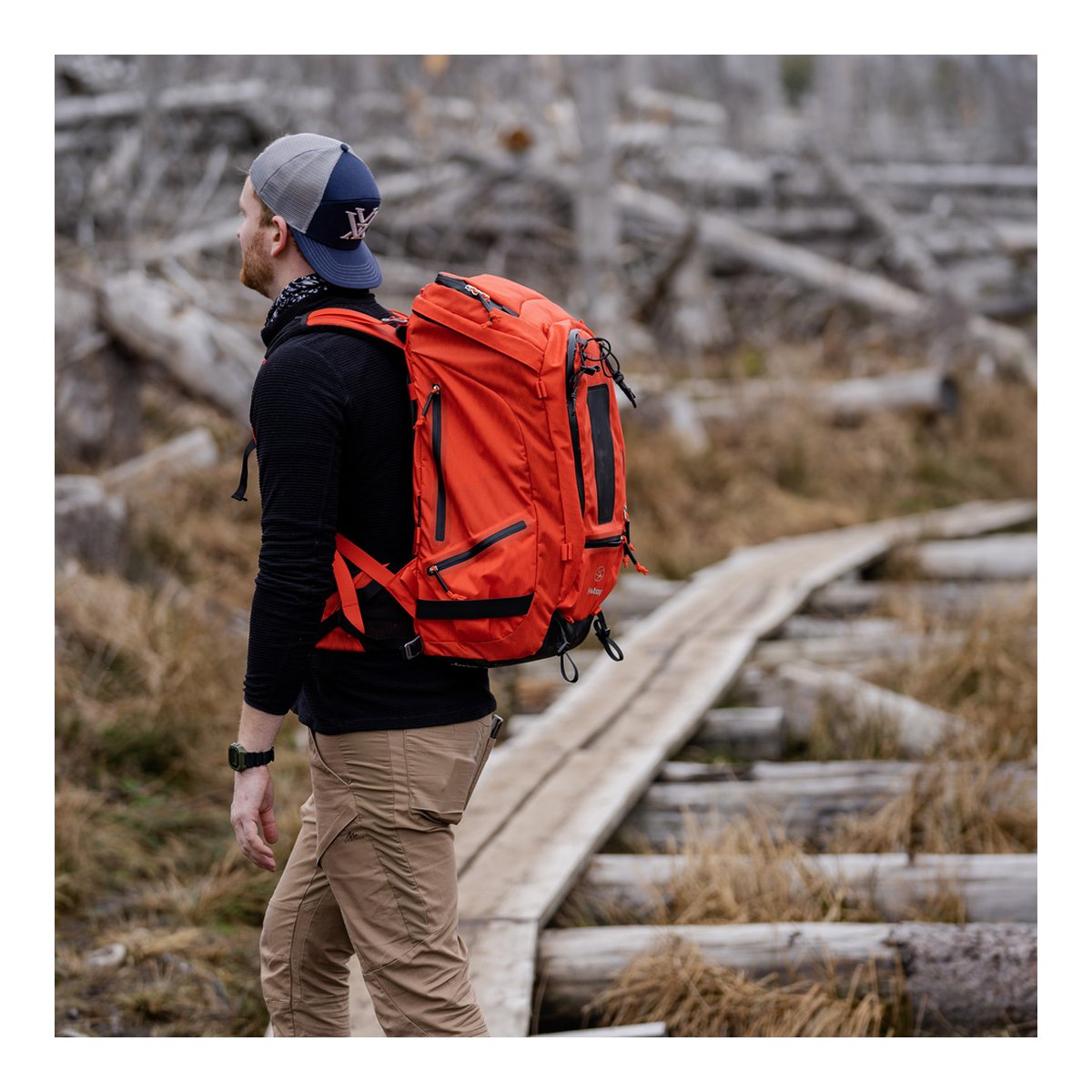 F-Stop DuraDiamond Tilopa - Magma - Anwendungsbeispiel: Orangefarbener Rucksack in 3/4-Rückansicht an einer Person auf Holzpfad. F-Stop DuraDiamond Tilopa - Magma - Anwendungsbeispiel: Orangefarbener Rucksack in 3/4-Rückansicht an einer Person auf Holzpfad.