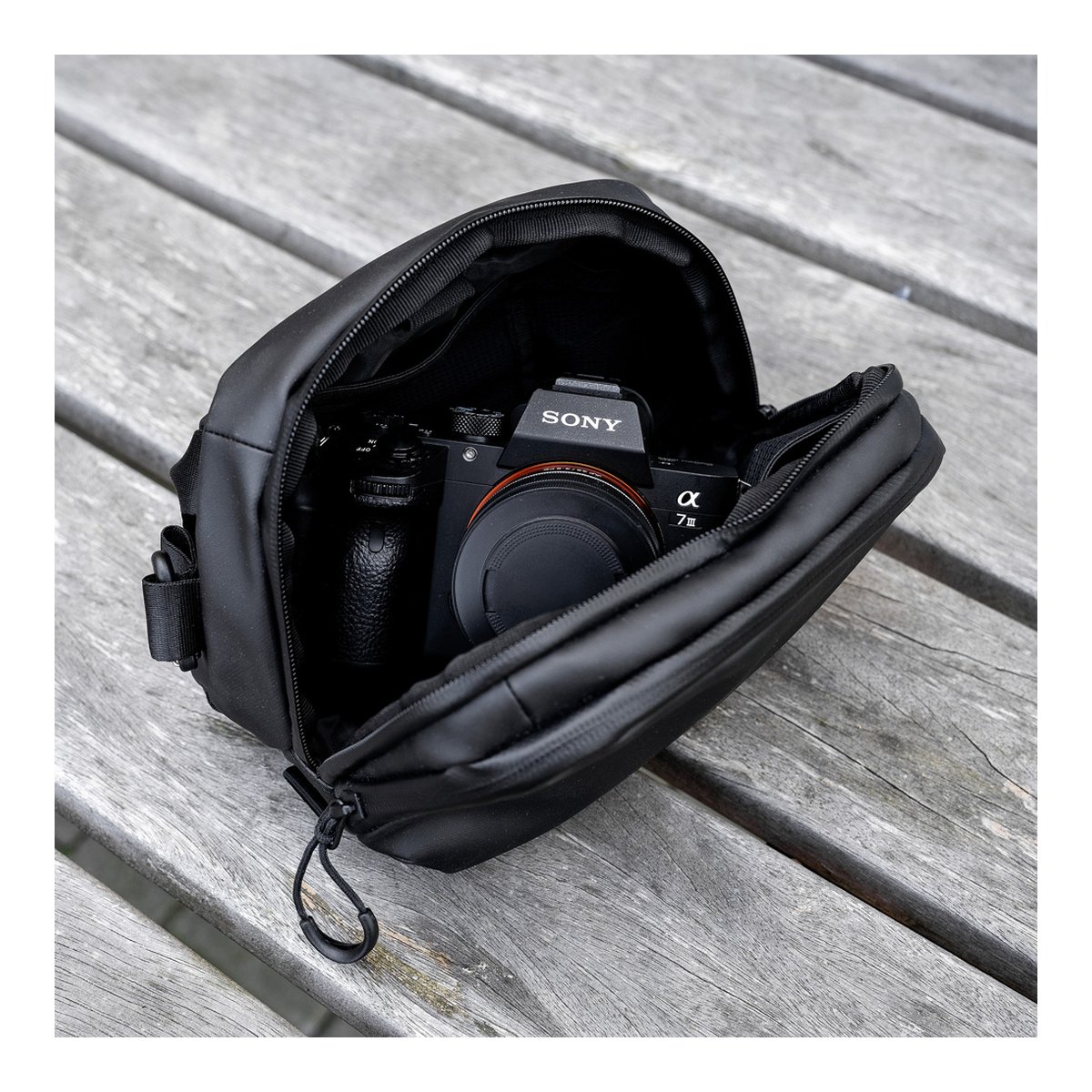 WANDRD Tech Bag Large - Grosse Organizer-Tasche (3,5 Liter) - Anwendungsbeispiel: Offene Tasche mit Sony Kamera auf Holztisch
