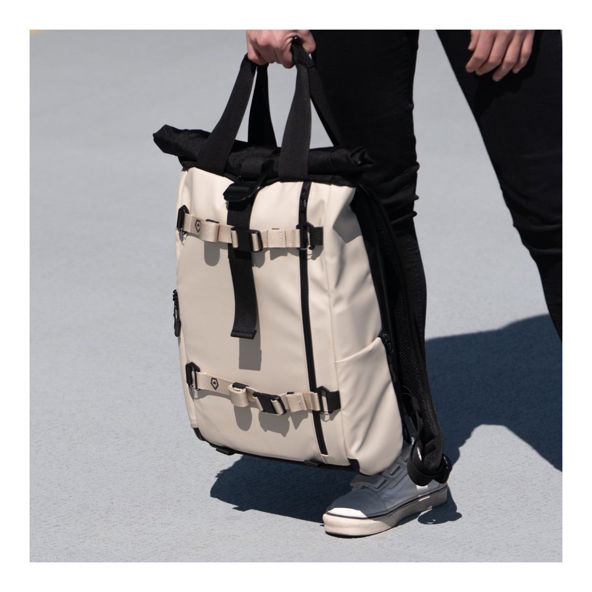 WANDRD PREMIUM ACCESSORY STRAP TAN V2 - Anwendungsbeispiel: Person trägt beigen Rucksack in der Hand.