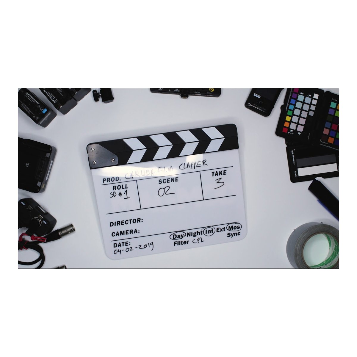 Caruba Professional Director Clapper Schwarz/BW (Whiteboardmarker) - Detailansicht Film-Clapperboard auf weißem Tisch, umgeben von Filmequipment.