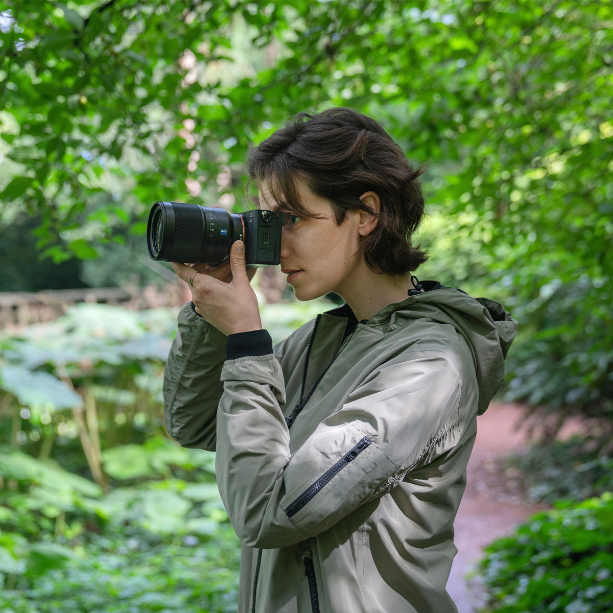 Frau mit der Sony Alpha 7C R im Gebüsch fotografiert
