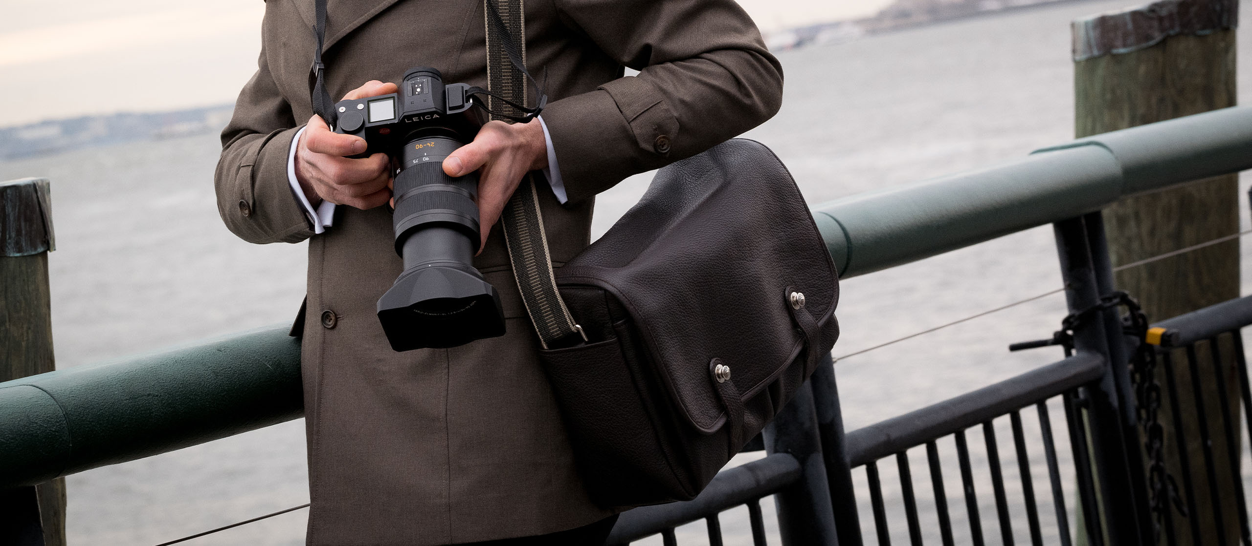 Oberwerth William Messenger und Kameratasche aus Leder hängt einem Mann mit einer Kamera in der Hand um die Schulter