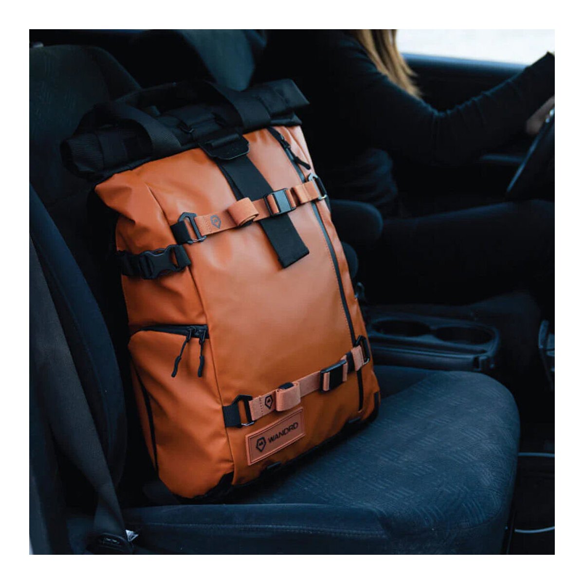 WANDRD PREMIUM ACCESSORY STRAP SEDONA ORANGE V2 - Produktanwendungsbeispiel: Brauner Rolltop-Rucksack auf Beifahrersitz im Auto