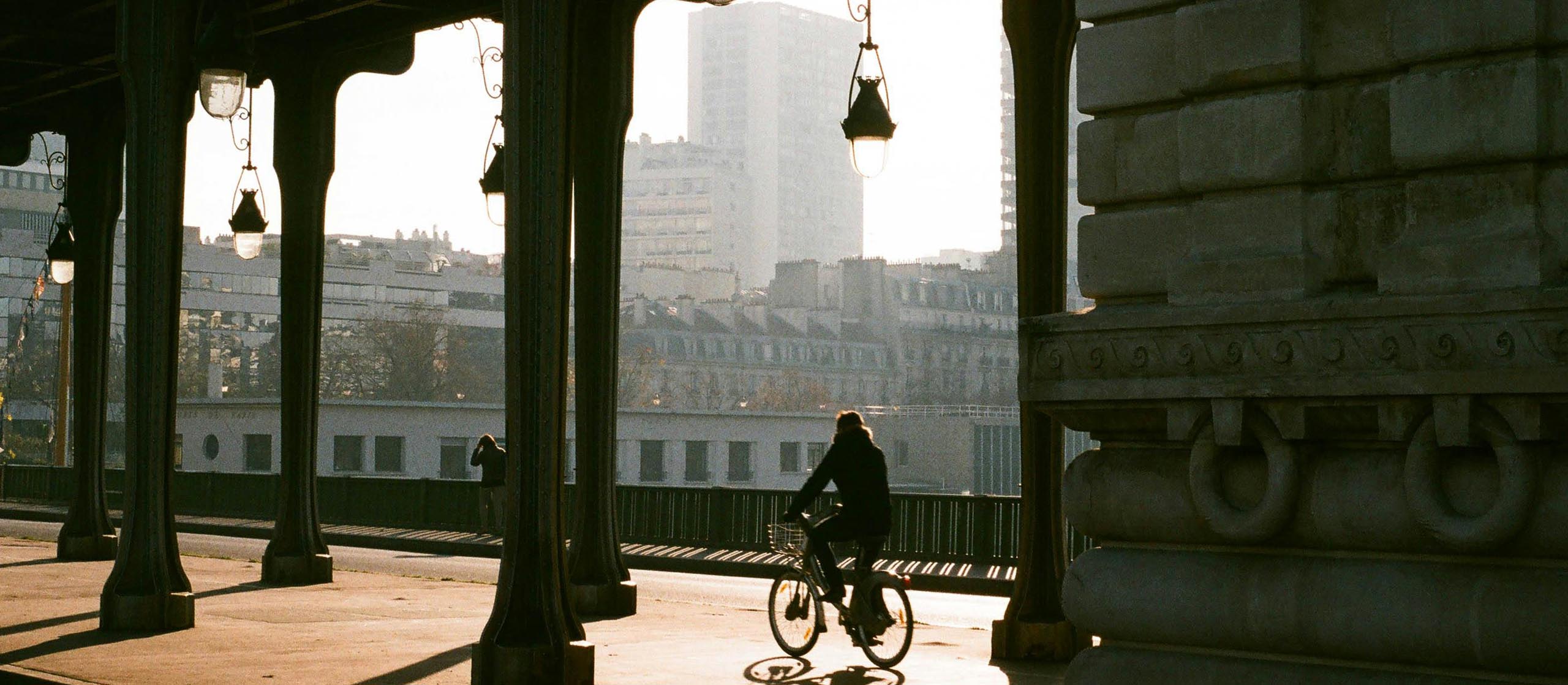 ThinkTank Retrospective – Stilvolle Schultertaschen für Stadtfotografie Radfahrer unter Brücke in der Stadt – Sinnbild für diskrete Fototaschen im urbanen Retro-Stil