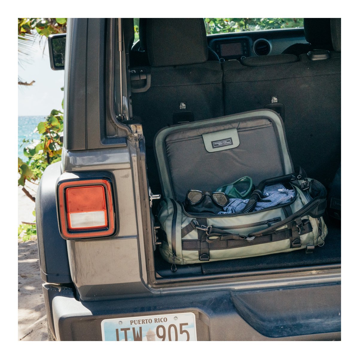 WANDRD HEXAD CARRYALL DUFFEL 40-Liter Wasatch Green - Anwendungsbeispiel: Grüne Reisetasche gepackt im Kofferraum eines Jeeps am Strand, bereit für das Abenteuer.
