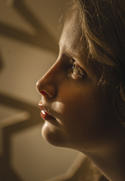 Low-Light-Porträt – Kreative Lichtsetzung für emotionale Wirkung Seitliches Porträt einer Frau in warmem Low-Light, das mit gezielter Lichtführung für eine stimmungsvolle Atmosphäre sorgt.