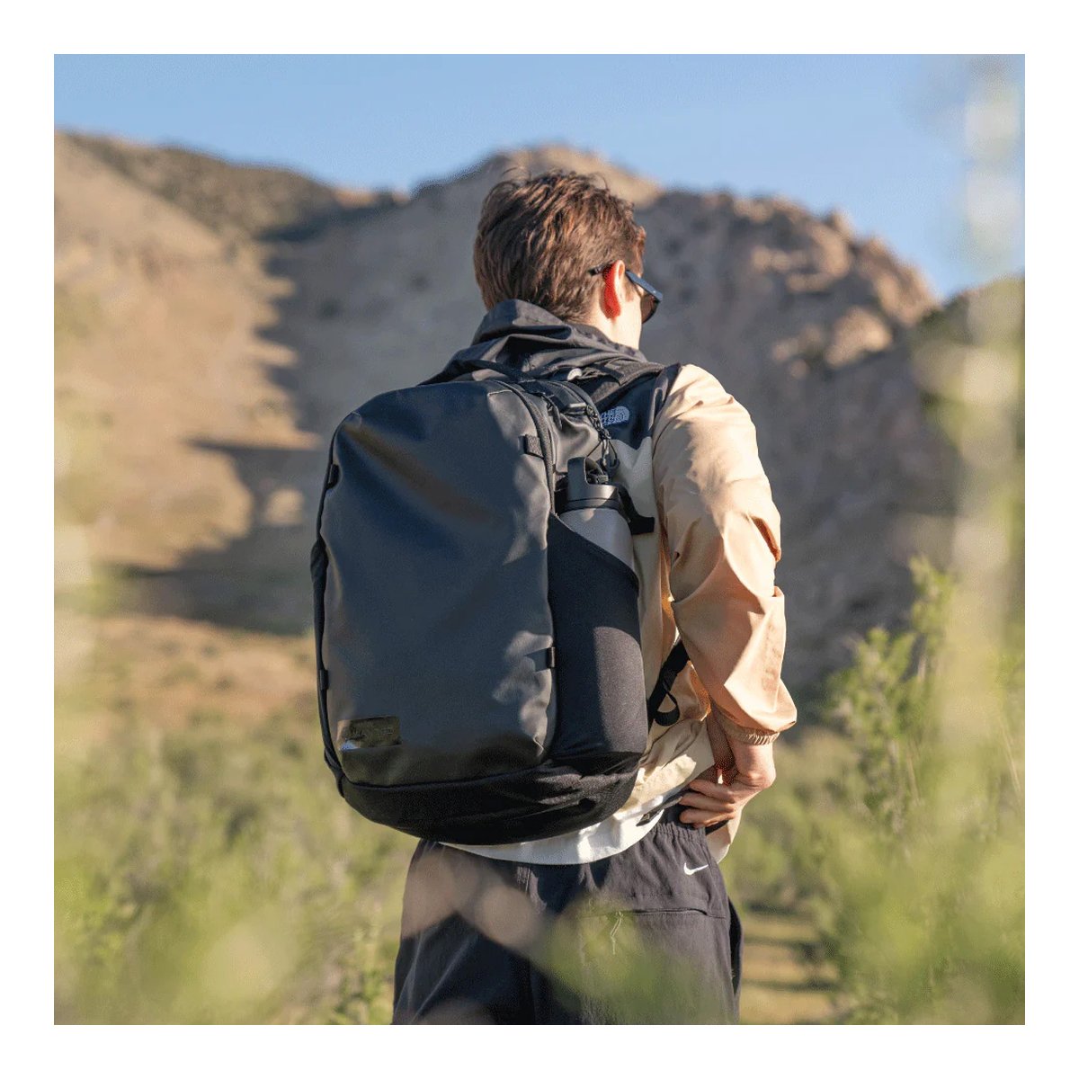 WANDRD NIMBUS 18 Black - Anwendungsbeispiel: Rückansicht einer Person mit schwarzem Rucksack in den Bergen.