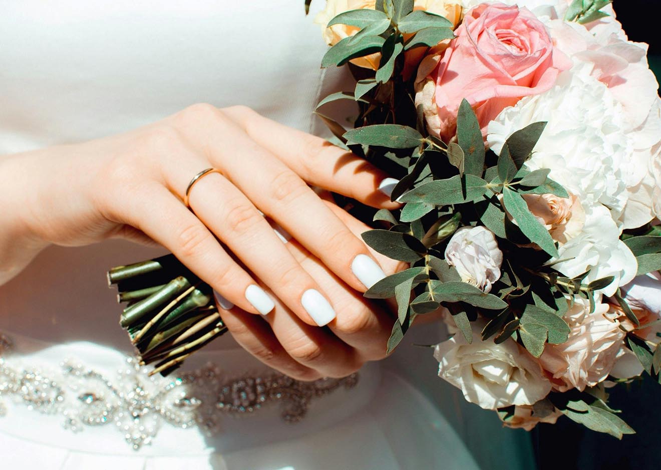 Detailaufnahme von Brautstrauß und Ehering Hand der Braut mit Ring und Blumen – klassische Detailaufnahme für Hochzeitsfotos